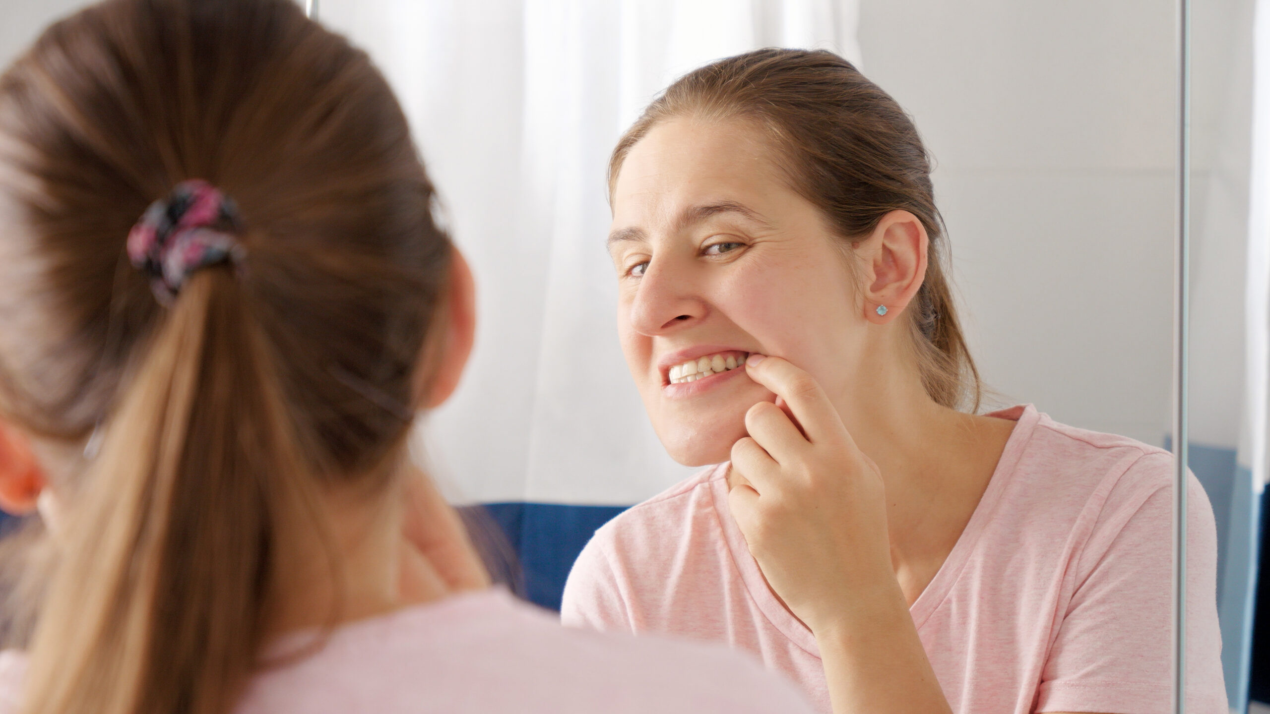 woman examining her teeth wondering if whitening damages enamel